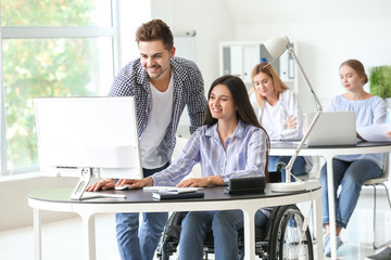 Handicapped young woman with colleague working in office