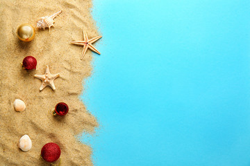 Beach sand with Christmas balls on color background