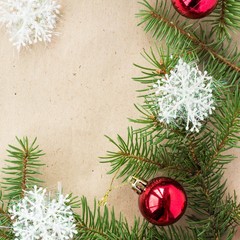 Festive christmas border with red balls on fir branches and snowflakes on rustic beige background