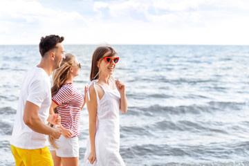 Happy friends running on sea beach at resort