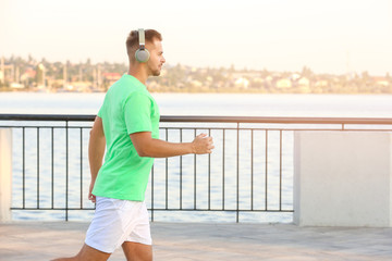 Handsome sporty man listening to music and running outdoors