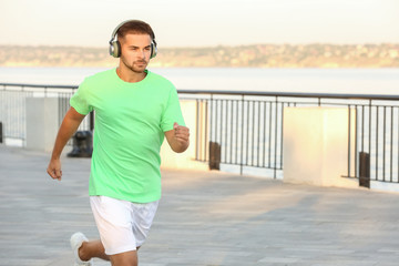Handsome sporty man listening to music and running outdoors