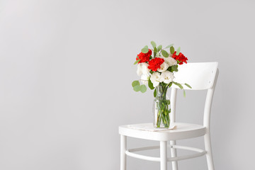 Vase with bouquet of beautiful flowers on chair