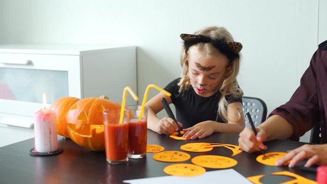 Concentrated Cute Little Girl Making Halloween Decorations from Colored Paper with her Mom. Halloween Holiday Concept