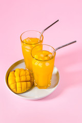 Glasses of fresh mango juice on color background