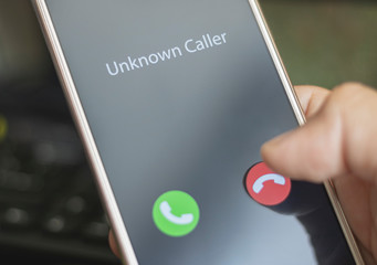 Unknown caller. A man holds a phone in his hand and thinks to end the call. Incoming from an unknown number. Incognito or anonymous