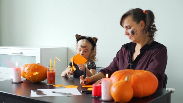 Young Mother and her Cute Little Daughter Preparing for Halloween. They are Making Halloween Decorations from Colored Paper