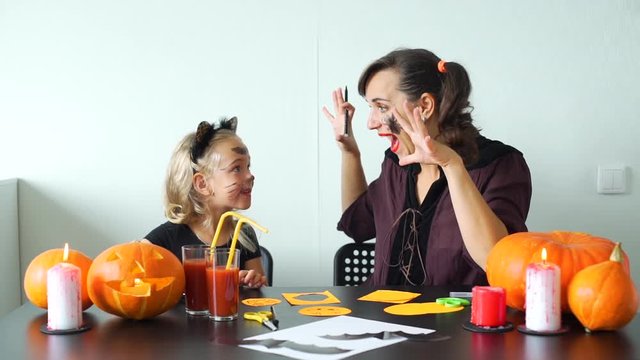 Young Mother and her Cute Little Daughter Having Fun while Preparing for a Halloween Celebration at Home. Slow Motion. Holidays and Halloween Decorations Concept