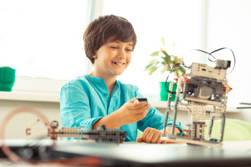 Cheerful boy being happy trying his robot model.