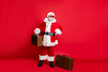 Full size photo of concentrated christmas father looking in eyewear eyeglasses holding packages planning newyear midnight trip isolated over red background