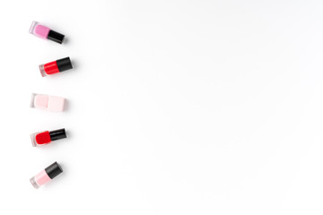Red and pink nail polishes on white background with copyspace. Top view