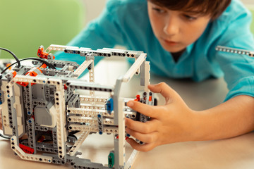 Serious schoolboy working on his complicated robot.