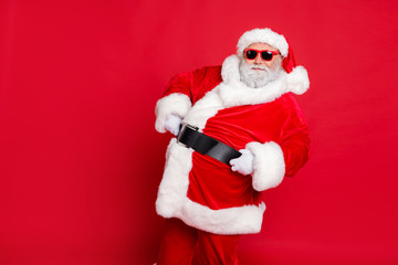 Fototapeta na wymiar Portrait of his he nice attractive cheerful cheery content bearded Santa showing eve noel festive festal mood holding belt isolated over bright vivid shine red background