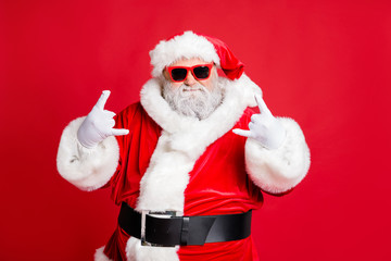 Portrait of his he funky confident content fat overweight plump gray-haired bearded man St Saint Nicholas having fun showing horn sign symbol isolated over bright vivid shine red background