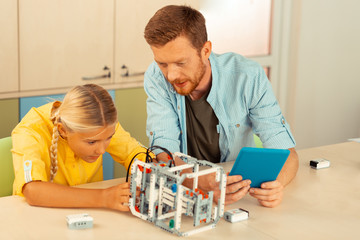 Teacher helping a schoolgirl building a robot.
