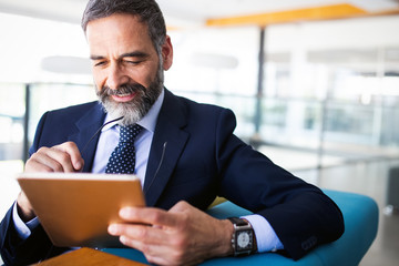 Mature handsome business man using a digital tablet at office