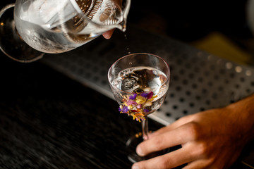 Bartender pours cocktail from glass with the strainer