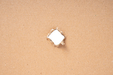 Ripped hole in cardboard on white background