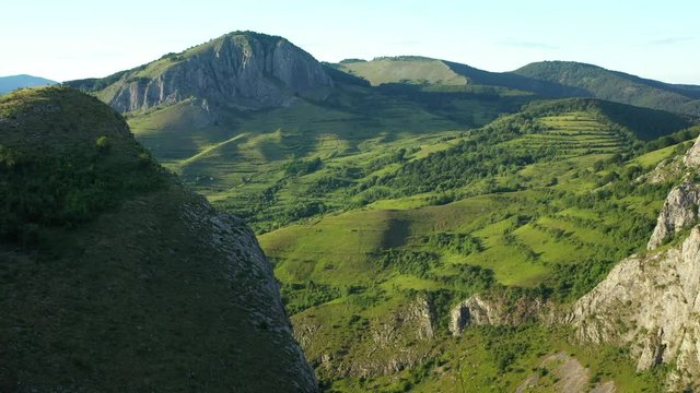 A wide angled fly over drone shot of the Coltesti mountain range, Romania. The valleys and gorges expand far into the distance.
