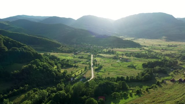 A wide angled fly over drone shot of the Coltesti mountain range, Romania. The valleys and gorges expand far into the distance, a windy road runs through the middle of the scenery.