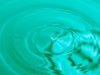 close up of a water drop falling and impact with a body of water