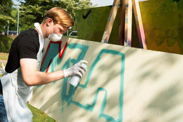 Teilnehmer beim Graffiti Workshop, kreativ mit Spraydose an der Leinwand
