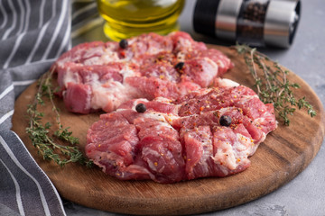 Slices of raw pork neck on wooden board. Closeup