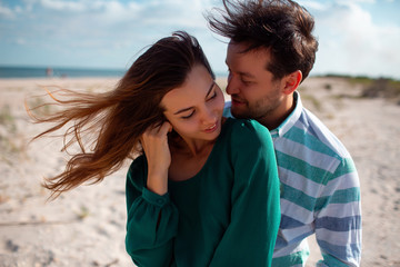 Fototapeta premium Romantic couple in love cuddling and kissing outdoors during sunset. Beautiful couple in love dating outdoors and smiling. Romantic couple on the beach.Horizontal copy space