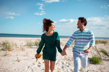 Couple walking on beach. Young happy interracial couple walking on beach smiling holding around...