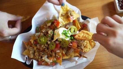 Woman hands eating Mexican nacho beef with cheese and cream