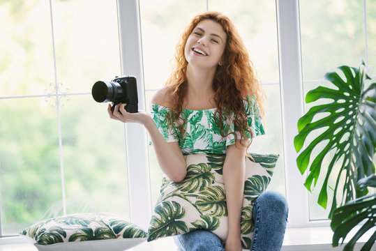 Happy woman using photo camera in modern light interior