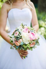 Obraz na płótnie Canvas bride holds a wedding bouquet in her hands