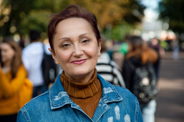 Woman in the city. Nice portrait of middle aged 50 years old woman walking on the street in autumn.