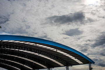 A sport hall showing an arch roof with metal and transparent sheets in between. Looking from the ground seeing with a nice clear sky in a background.