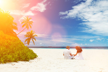 Fototapeta na wymiar Happy honeymoon vacation at summer. Couple relax on the white sand of beach. Happy sea lifestyle. Young family, man and woman rest on the beach of ocean. Couple in love travel to island. Love travel