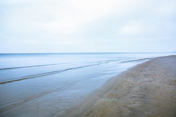 Grey sea. Cold seaside background. Baltic nature. Sand texture on the beach. Winter season.
