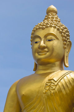 Close-up of a golden buddha statue against the blue sky on the island of Phuket in Thailand. The figure of the Golden Buddha on Mount Nakaked in honor of the Queen of Thailand.