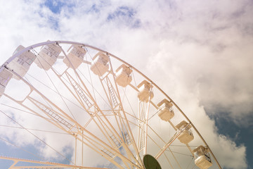 Ferris wheel on the colorful cloudy sky. Background concept of happy holidays time.