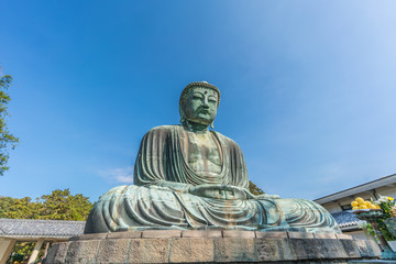 Monumental outdoor bronze statue The Great Buddha in Kamakura, Japan. Wide angle view with clear blue sky 