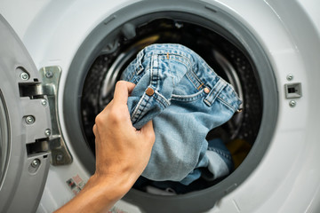 Putting Jeans into the washing machine - obrazy, fototapety, plakaty