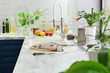 Raw fish for cooking with vegetables on the kitchen table.