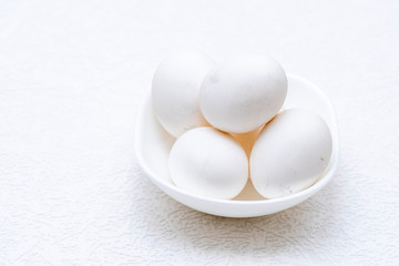 Whole white eggs in a white bowl
