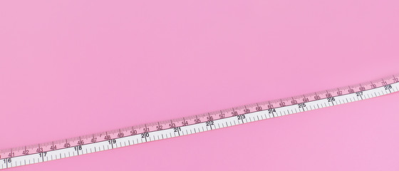close up of measure tape on pink background