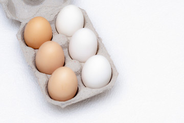 Three white and three brown eggs in a cardboard tray