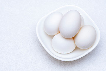 Close up shot of whole white eggs in a white bowl