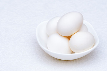 Close up shot of whole white eggs in a white bowl