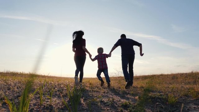 Happy family walks in the park in the sun at sunset. Mom, dad and baby happy walk at sunset. Joint family walks healthy lifestyle. The concept of a happy family and family values