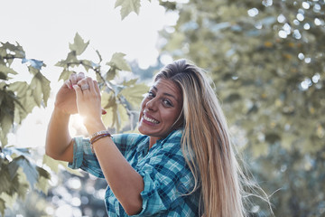 Young woman outdoors making heart - shape symbol for love and romance.