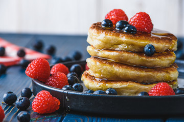 Pancakes with honey and berries on a wooden table