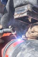 Construction worker welding pipes on a heavy site.